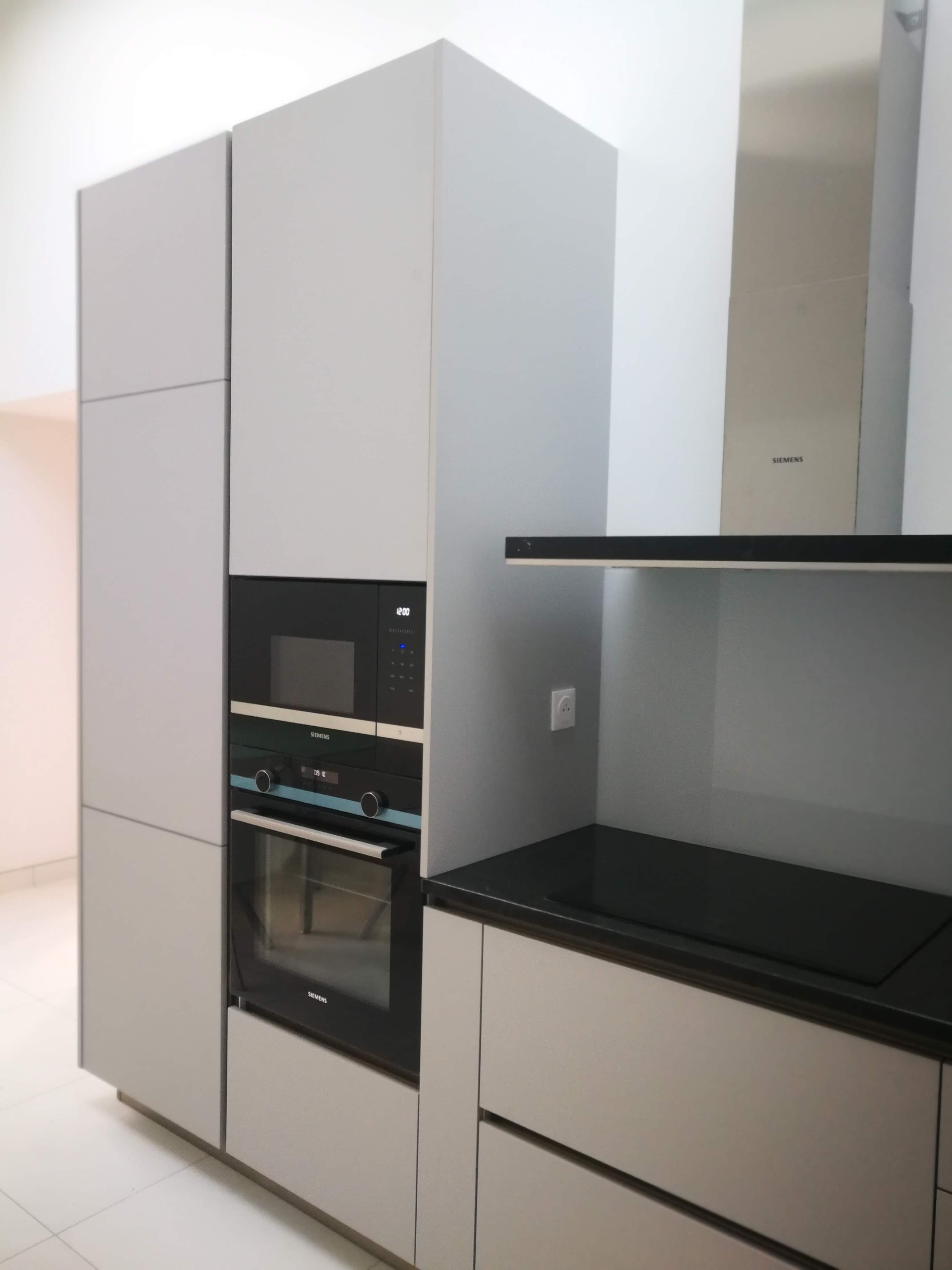 Cozinha em mansarda com coluna Siemens encastrada, armarios cinza, bancada preta e exaustor inox