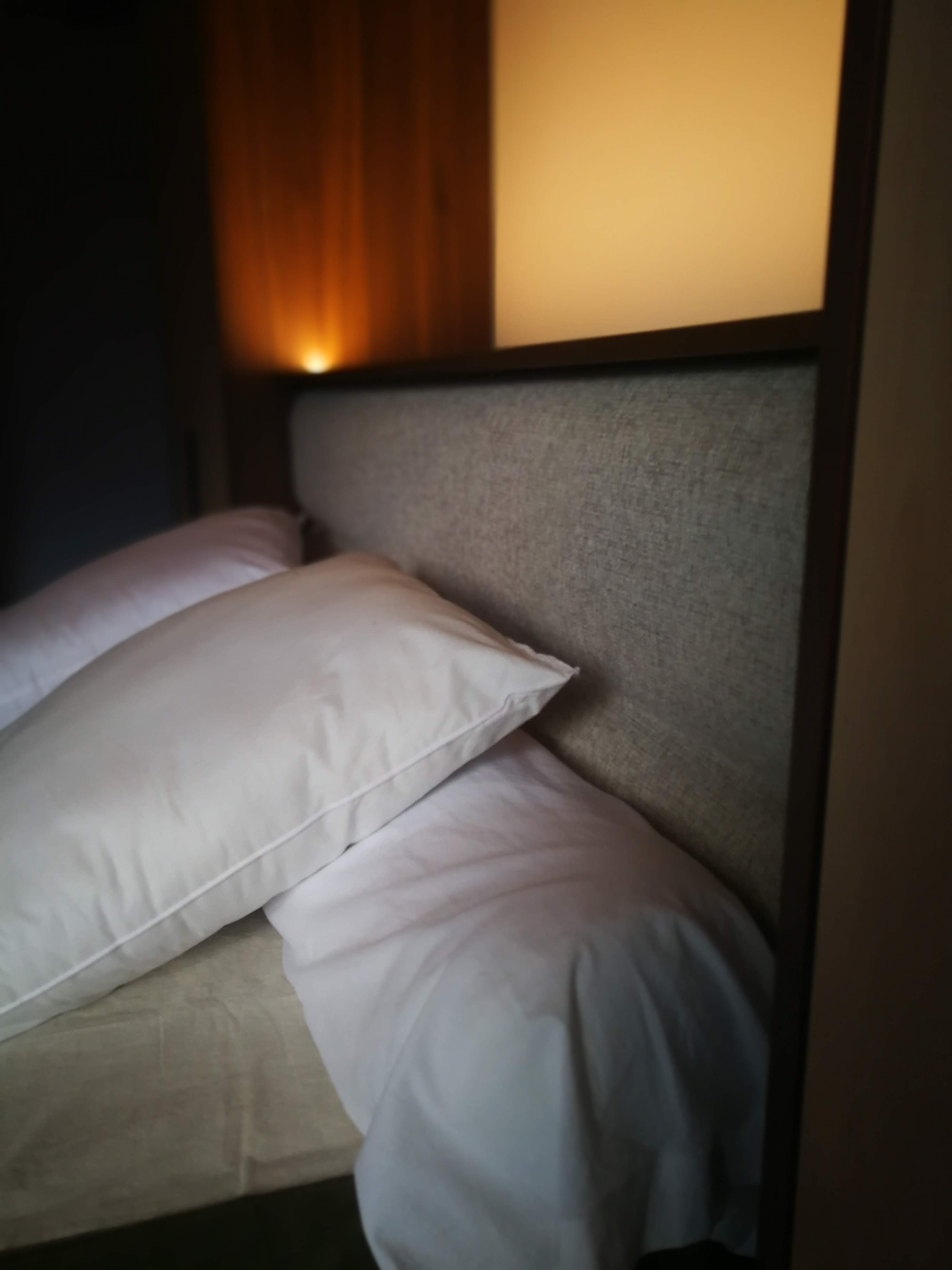 Detalhe da cabeceira com painel estofado cinza e nicho iluminado em nogueira