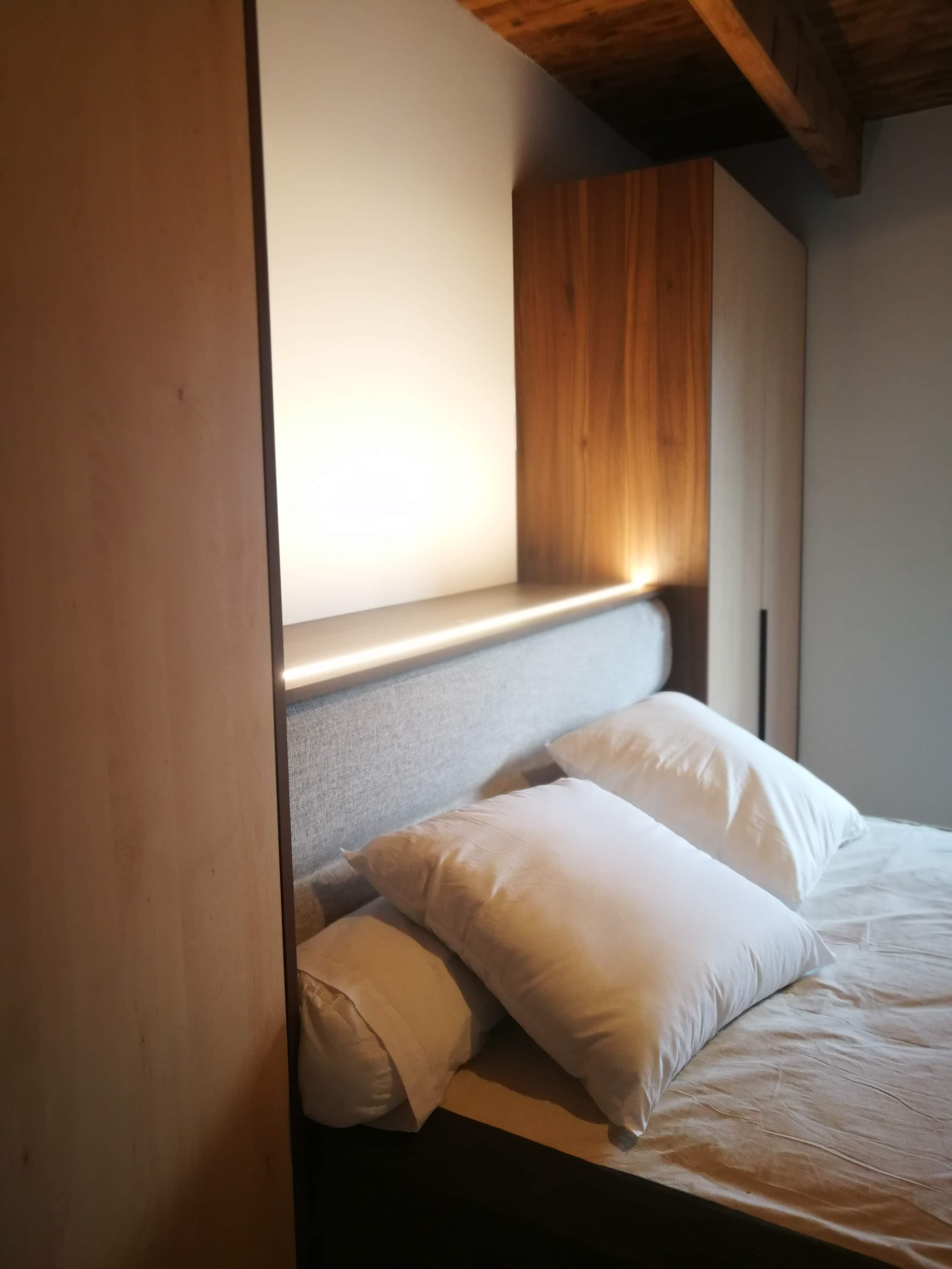 Painel em nogueira com LED integrada, armario lateral em madeira clara e vigas rusticas no teto