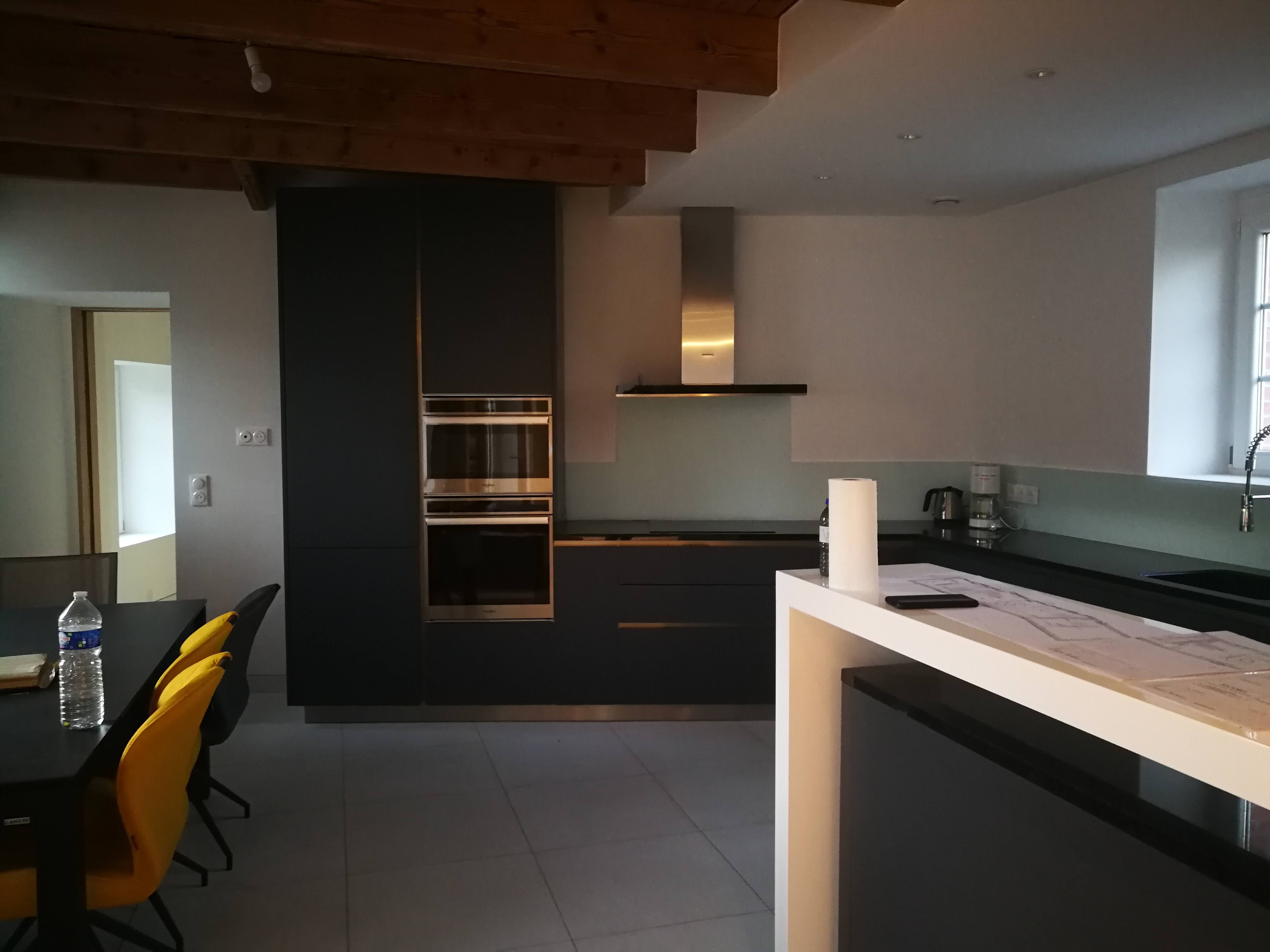 Casa de banho com duche em vidro, pedra natural bege, movel branco lacado e janela normanda com vista jardim